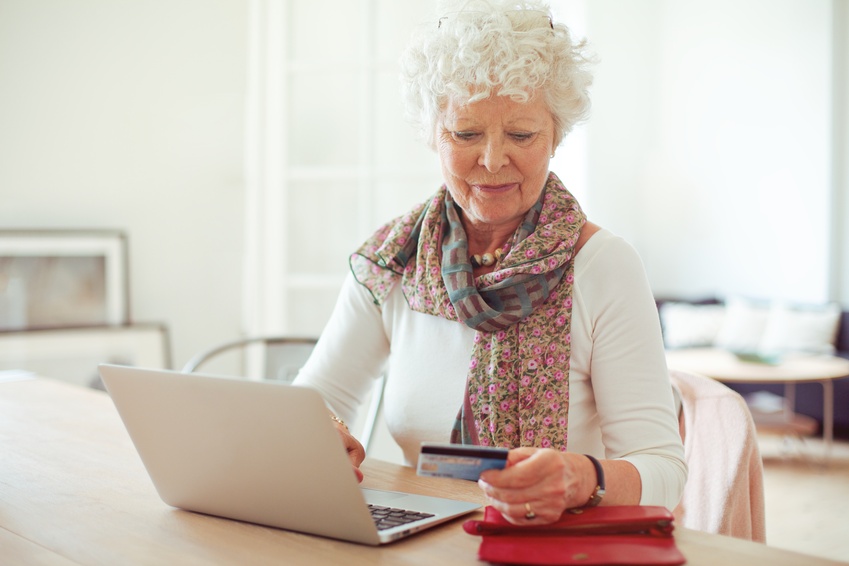 Grandmother in front of laptop paying online using a credit card