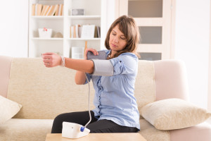 Beautiful woman checking her blood pressure at home