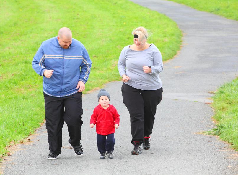 Overweight parents with her son running together.