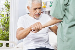 Disabled Patient Holding Hand Of Nurse In Rehab Center