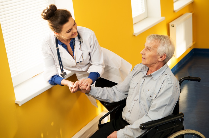 Cheerful young nurse woman with senior man in wheelchair