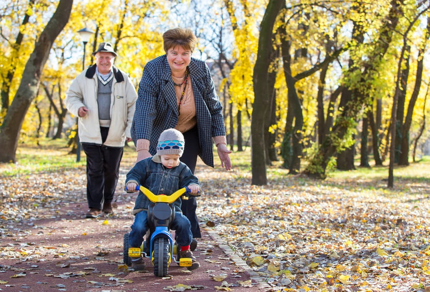 happy grandparents and grandchild have fun and play in park