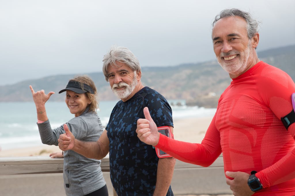 Smiling senior friends exercising on a beach in Portugal, embracing a healthy lifestyle.
